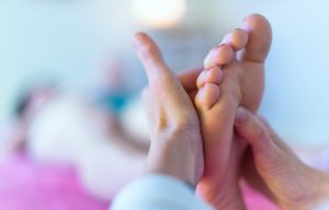 Therapist's hands massaging female foot