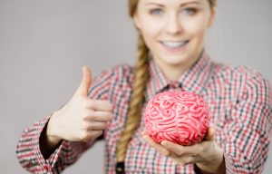 Woman thinking and holding fake brain
