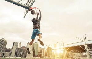 Basketball street player making a rear slam dunk.