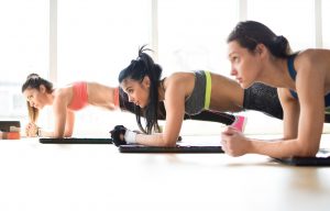 Three attractive sport girls doing plank exercise in fitness class.