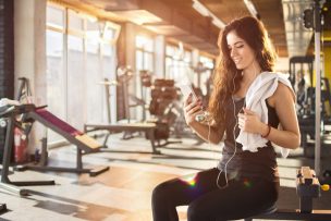 Attractive girl with earphones listening to music in gym.