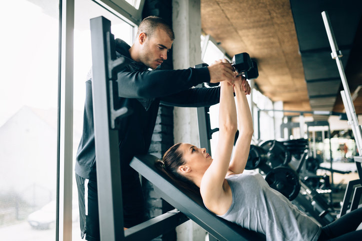 Beautiful woman helped by trainer