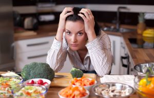 A frustrated woman looking out at salad bowls in her kitchen