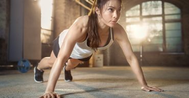 Athletic Beautiful Woman Does Push-ups as Part of Her Cross Fitness, Bodybuilding Gym Training Routine.