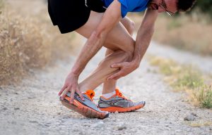 close up of runner touching painful twisted or broken ankle shin or calf athlete runner training accident sport running ankle sprain concept