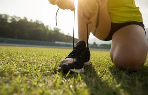 Young fitness woman runner tying shoelace on stadium tracks